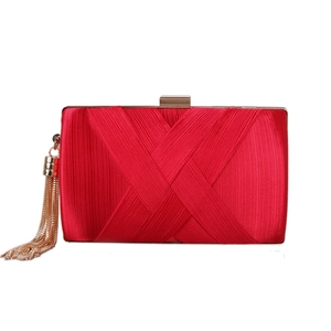 Detail of red satin evening clutch with cross-pleated texture and gold tassel