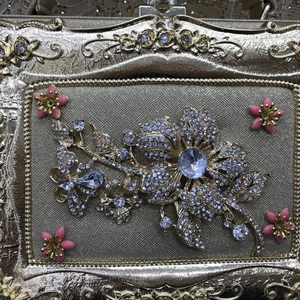 Detail of gold evening bag featuring crystal flower inlay and pink enamel floral accents