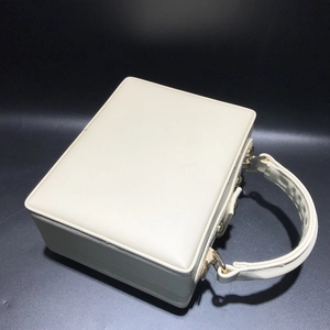 Détail d'un sac à main beige crème en forme de boîte avec fermoir en métal doré