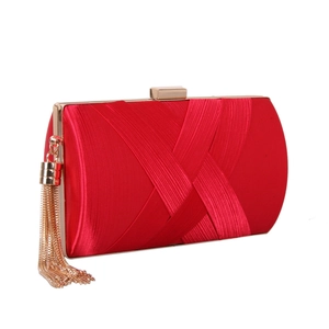 Close-up of red silk evening bag with pleated texture and gold chain tassel detail