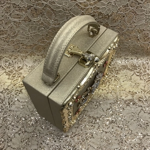 Detail of luxury gold evening bag featuring diamond clasp and floral crystal accents