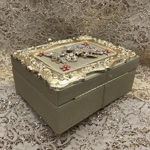 Detail of vintage champagne gold jewelry box with butterfly rhinestones and floral relief