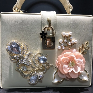 Sac à main rigide blanc crème avec roses en tissu 3D, perles et strass sur fond noir