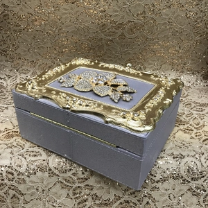 Detailed view of luxury purple leather box with golden floral embossed pattern and rhinestones