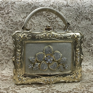 Macro view of golden evening clutch featuring sparkling rhinestone flower and baroque relief