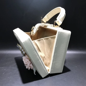 Détail de la pochette boîte blanche ouverte avec fleurs 3D et décorations satinées