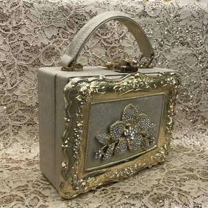 Close-up of gold box evening bag with sparkling crystal flowers and ornate carvings