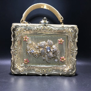 Detail of golden evening clutch featuring floral rhinestone patterns and metal frame