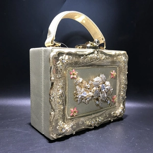 Detail of gold evening handbag featuring floral metal relief and sparkling crystals