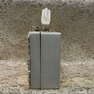 Macro detail of champagne box clutch bag showing saffiano texture and gold hardware