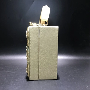 Detail view of the side profile and gold metal floral texture of the luxury evening clutch bag