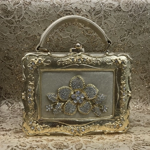 Detail of golden box evening bag featuring ornate floral rhinestone decor and antique texture