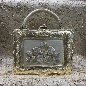 Detail view of golden evening bag featuring intricate rhinestone floral and leaf motifs