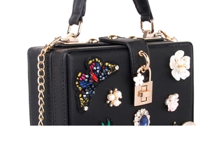Détails de broderie florale et de perles sur une pochette rigide noire pour femme