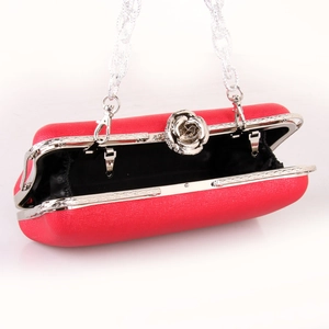 Detail of red leather evening clutch featuring a rose-shaped silver metal clasp and chain