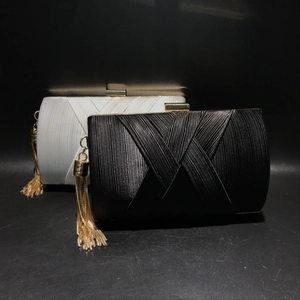 Detail view of woven silk evening clutch bag with fringe chain and gold snap closure