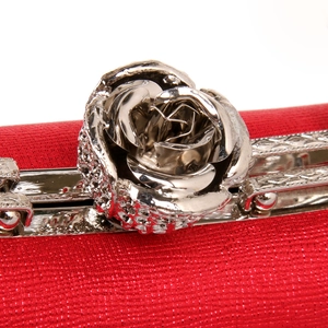 Close-up of red evening clutch featuring an elegant silver metal rose-shaped buckle