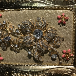Macro shot of gold floral brooch with sparkling rhinestones and pink enamel petals