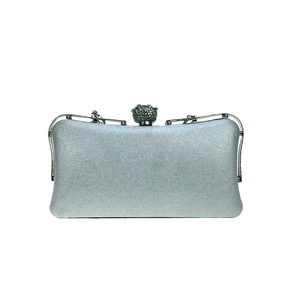 Detailed shot of silver evening clutch bag featuring a sparkling rhinestone sphere clasp