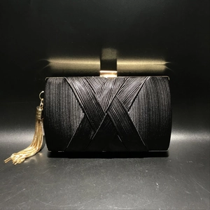 Detail of black silk woven evening clutch bag with gold tassel and rectangle clasp
