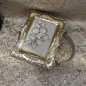 Macro detail of golden evening bag featuring intricate floral rhinestone pattern and metal frame