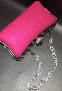Detail of fuchsia glitter clutch bag with silver metal frame and rhinestone clasp
