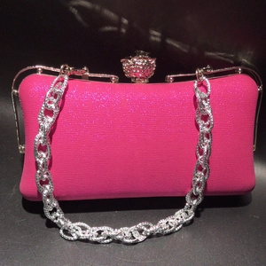 Detailed close-up of fuchsia leather evening bag with floral rhinestone clasp and silver chain