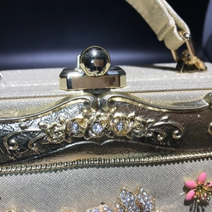 Detail of golden evening bag with rose relief and crystal encrusted ball clasp