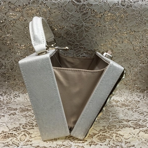 Detail view of the open cream leather evening bag with gold metal frame and silk lining