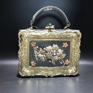 Detail of floral rhinestone embellishments and vintage gold frame on black evening bag