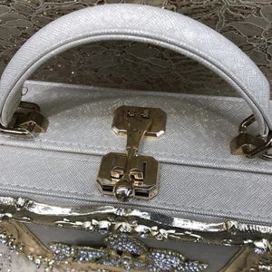 Close-up of silver glitter evening bag with gold metal lock and rhinestone crown detail