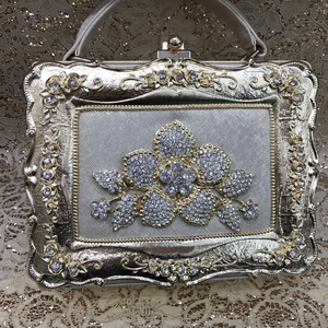 Macro detail of golden evening clutch featuring floral rhinestone brooch and relief pattern