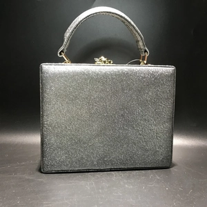 Close-up of a silver glitter evening clutch bag with square frame and gold metal clasp