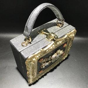 Detail of silver sequined evening box bag with rhinestone carriage and gold hardware