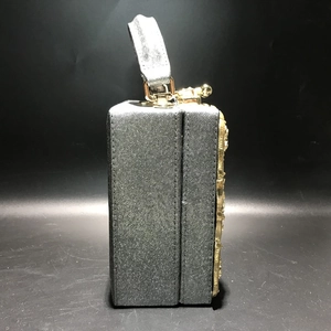 Macro side view of silver glitter evening bag with ornate gold floral embossed metal panels