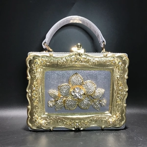 Detail of vintage box clutch featuring golden relief frame and crystal floral centerpiece