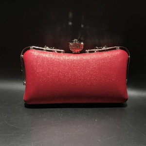 Close-up of red evening clutch featuring textured faux leather and silver floral clasp