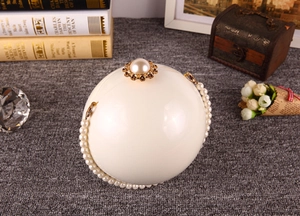 Détail d'un sac de soirée sphérique en perles avec poignée perlée et bordure dorée