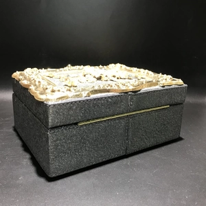 Close-up of vintage jewelry box with golden floral relief and blue gemstone inlay