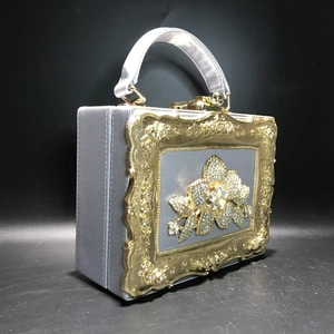 Close-up of ornate gold frame and crystal floral pattern on silver evening clutch bag