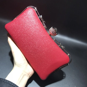Close-up of red glitter clutch bag featuring a floral rhinestone clasp and silver metal frame