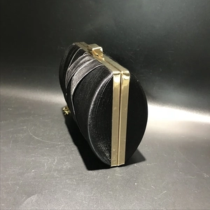 Detail of black silk woven evening bag featuring gold metal frame and texture
