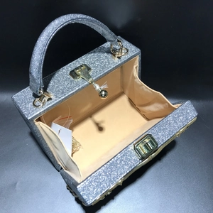 Macro view of silver glitter evening bag showing inner lining and gold metal chain