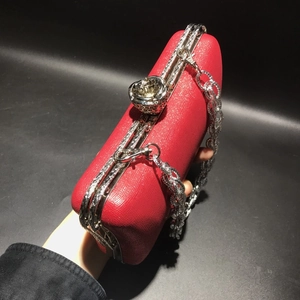 Detail of red leather evening clutch featuring a silver 3D rose clasp and chain strap
