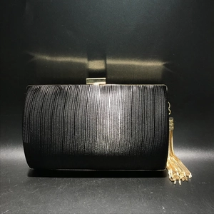 Close-up of black pleated fabric evening bag with gold tassels and metallic buckle