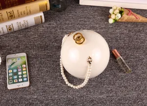Gros plan d'un sac de soirée sphérique blanc en acrylique avec anse en perles chic