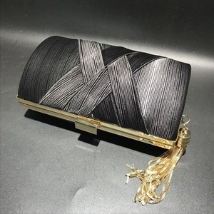 Detail of silk pleated evening bag featuring gold metal frame and long tassel ornament