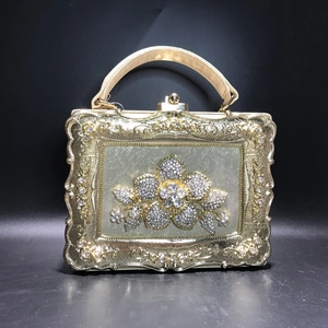 Close-up of golden evening clutch bag featuring intricate floral rhinestone patterns