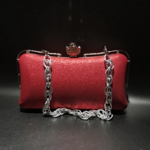 Detail view of the red leather evening clutch bag with ornate silver clasp and chain strap