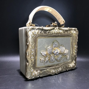 Detail of luxury box clutch with gold floral carving and crystal flower inlay decoration